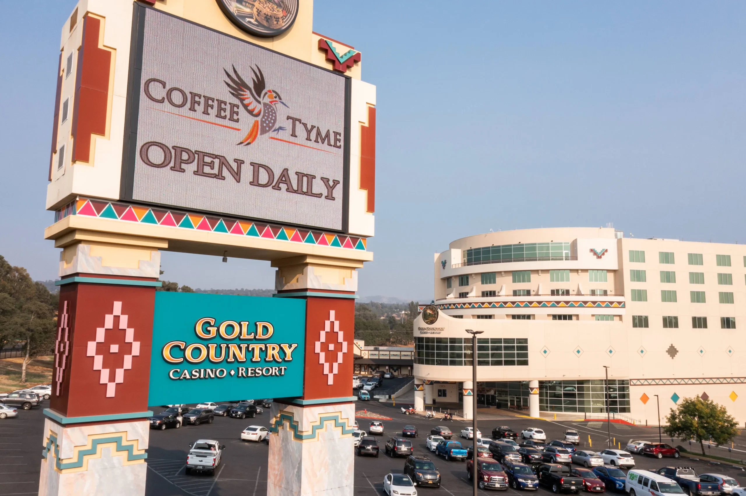 Gold Country_RV Park_Drone-151 Large sign for Gold Country Casino Resort and Coffee Tyme stands above a parking lot with many cars; multi-story casino building is visible in the background.